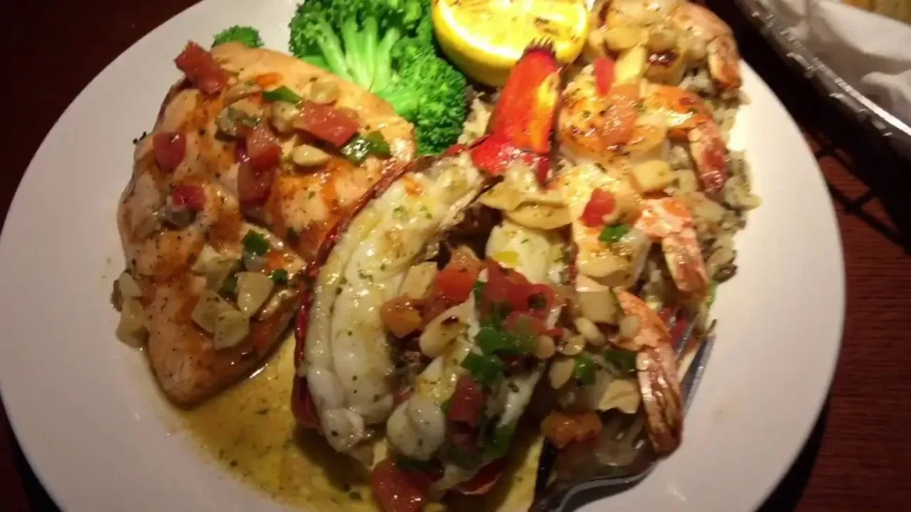 Fresh ingredients for Grilled Lobster, Shrimp and Salmon including lobster tail, shrimp, salmon, garlic butter, herbs, and lemon